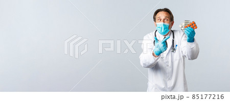 Covid-19, preventing virus, healthcare workers and vaccination concept. Excited doctor in medical mask and gloves pointing finger at medicine, showing medication, recommend pills Covid-19, preventing virus, healthcare workers and vaccination concept. Excited doctor in medical mask and gloves pointing finger at medicine, showing medication, recommend pills 85177216