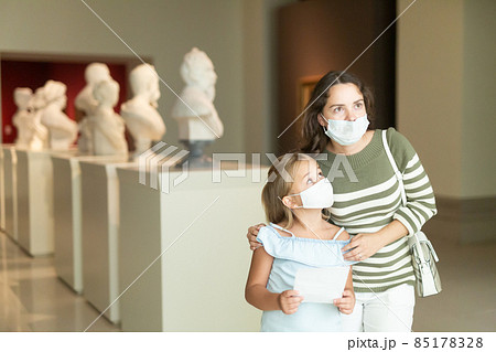 Woman visitor with daughter looking at exhibition in museum 85178328
