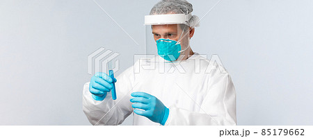 Covid-19, preventing virus, healthcare workers and vaccination concept. Serious-looking doctor in personal protective equipment carefully examine test tube with vaccine sample Covid-19, preventing virus, healthcare workers and vaccination concept. Serious-looking doctor in personal protective equipment carefully examine test tube with vaccine sample 85179662