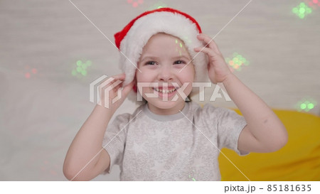 little child laughs in Santa hat, kid smile Christmas holidays, happy family, baby has fun playing bright colors of garland, festive mood in new year, waiting for miracle child dream, time for gifts little child laughs in Santa hat, kid smile Christmas holidays, happy family, baby has fun playing bright colors of garland, festive mood in new year, waiting for miracle child dream, time for gifts 85181635