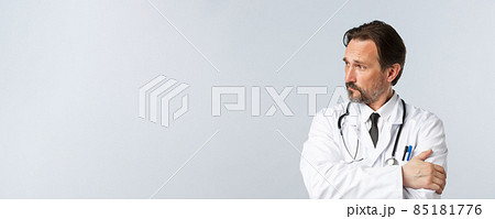 Covid-19, preventing virus, healthcare workers and vaccination concept. Thoughtful concerned doctor in white coat and stethoscope, looking left worried, thinking, making important decision 85181776