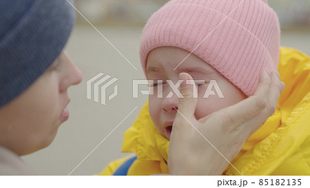 the little child is crying, bitter tears are streaming down kid cheeks, the mother calms the capricious daughter, girl is upset and roars, maternal care and care for baby, children's nervous tremors 85182135