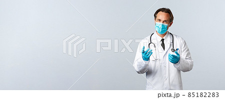 Covid-19, preventing virus, healthcare workers and vaccination concept. Serious-looking doctor in medical mask and gloves have conversation with patients, explain measures during coronavirus pandemic 85182283