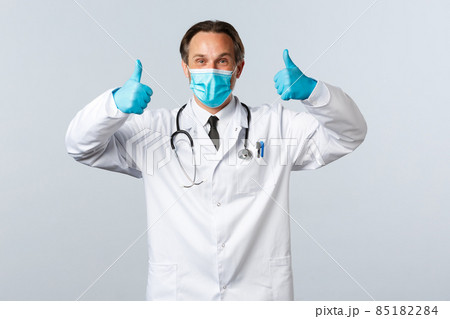 Covid-19, preventing virus, healthcare workers and vaccination concept. Enthusiastic happy doctor in medical mask and gloves guarantee quality, show thumbs-up in approval or like Covid-19, preventing virus, healthcare workers and vaccination concept. Enthusiastic happy doctor in medical mask and gloves guarantee quality, show thumbs-up in approval or like 85182284