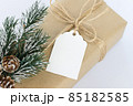 Christmas and New Years background close-up. Gift box wrapped in kraft paper with jute cord. Decorated with a label and a branch with cones 85182585