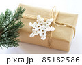 Christmas and New Years background close-up. Gift box wrapped in kraft paper with jute cord. Decorated with a crocheted snowflake and a branch 85182586