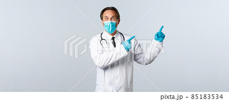 Covid-19, preventing virus, healthcare workers and vaccination concept. Shocked startled male doctor in mask and gloves, pointing upper right corner impressed, promote banner Covid-19, preventing virus, healthcare workers and vaccination concept. Shocked startled male doctor in mask and gloves, pointing upper right corner impressed, promote banner 85183534