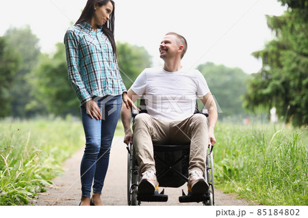 Man sit in wheelchair, female visitor spend time with friend at nursing house 85184802