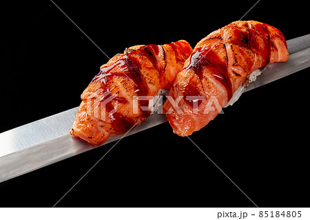 Nigirizushi with fried salmon and unagi sauce on thin blade of Japanese knife isolated on black Nigirizushi with fried salmon and unagi sauce on thin blade of Japanese knife isolated on black 85184805