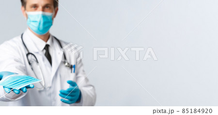 Covid-19, virus, healthcare workers and vaccination concept. Doctor in PPE handing you medical mask, explain preventive measures not catching coronavirus disease, worry patient health Covid-19, virus, healthcare workers and vaccination concept. Doctor in PPE handing you medical mask, explain preventive measures not catching coronavirus disease, worry patient health 85184920