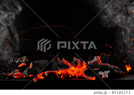 Hot burning coals on barbecue tray on black background with sparks and white smoke 85185171