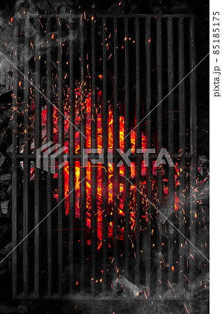 Top view through black barbecue grate of burning coals with sparks and white smoke Top view through black barbecue grate of burning coals with sparks and white smoke 85185175
