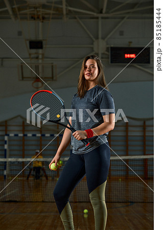 Female tennis player with racket and ball on gym background 85185444