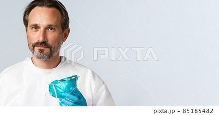 Covid-19, preventing virus, healthcare and vaccination concept. Smiling doctor take-off medical respirator and looking camera, working with patients sick coronavirus, wear PPE 85185482