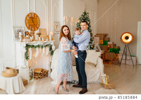 happy family in the room in front of sofa, the fireplace and Christmas tree.  85185884