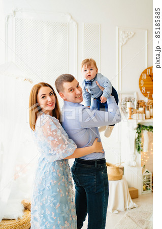 dad holds the baby son in his hands, and mom hugs.  85185885