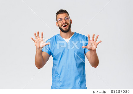 Healthcare workers, medicine, covid-19 and pandemic self-quarantine concept. Excited smiling doctor, happy nurse in glasses and blue scrubs, show hands, number ten, grey background Healthcare workers, medicine, covid-19 and pandemic self-quarantine concept. Excited smiling doctor, happy nurse in glasses and blue scrubs, show hands, number ten, grey background 85187086