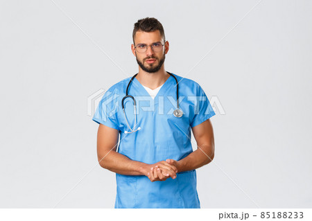Healthcare workers, medicine, covid-19 and pandemic self-quarantine concept. Serious-looking determined, professional doctor or intern, nurse in blue scrubs and glasses, talking to patient Healthcare workers, medicine, covid-19 and pandemic self-quarantine concept. Serious-looking determined, professional doctor or intern, nurse in blue scrubs and glasses, talking to patient 85188233