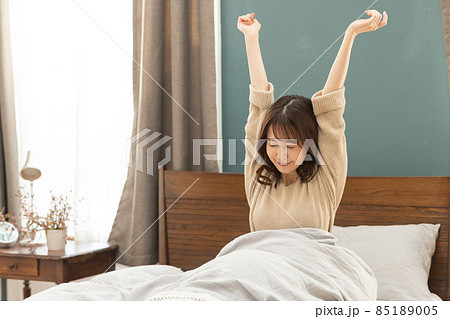 ベッドから起きる若い女性 85189005