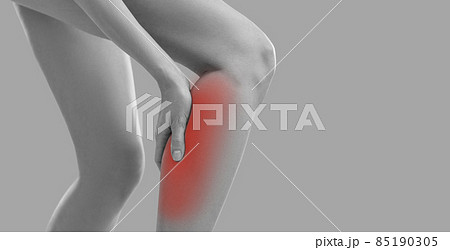 Woman touches her calf as she has sudden leg cramp. Young lady feels pain in torn or overstretched muscle. Girl suffers from pain due to injury, rare rheumatism symptom or after overtraining at gym 85190305