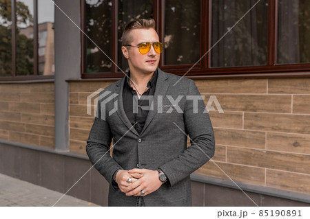 Stylish young guy portrait businessman of European appearance in a gray jacket and black shirt in sunglasses on the street outdoor Stylish young guy portrait businessman of European appearance in a gray jacket and black shirt in sunglasses on the street outdoor 85190891
