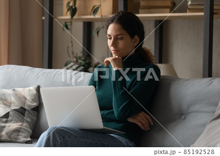 Pensive young Latin woman work on laptop thinking 85192528