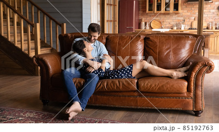 Affectionate happy young family couple relaxing on cozy sofa. Affectionate happy young family couple relaxing on cozy sofa. 85192763