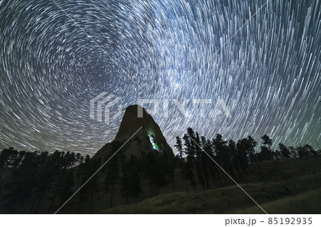 Star Trails over Devils Tower Butte at Night. Light Flare of Climbers on a Wall. Wyoming, USA Star Trails over Devils Tower Butte at Night. Light Flare of Climbers on a Wall. Wyoming, USA 85192935