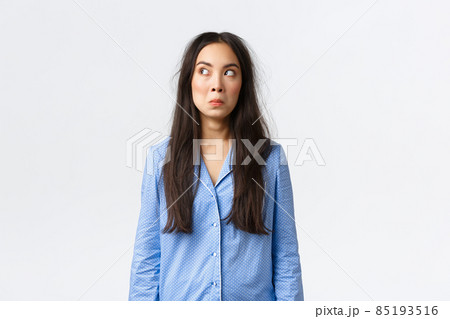 Confused and puzzled cute asian girl with messy hair, wearing blue pajamas, waking up morning, looking questioned at upper left corner, overslept, standing clueless white background Confused and puzzled cute asian girl with messy hair, wearing blue pajamas, waking up morning, looking questioned at upper left corner, overslept, standing clueless white background 85193516