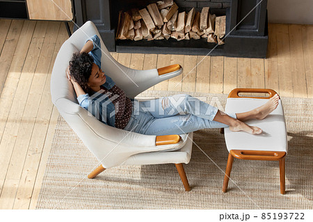 African woman relax on armchair in cottage house with fireplace 85193722