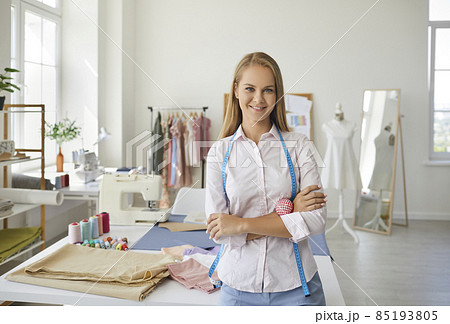 Portrait of smiling young Caucasian woman seamstress tailor pose in own fashion atelier. Happy millennial female designer or stylist in handmade workshop, own small creative business. Hobby concept. 85193805
