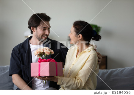 Excited middle aged mom receiving surprise gift and flower bunch 85194056