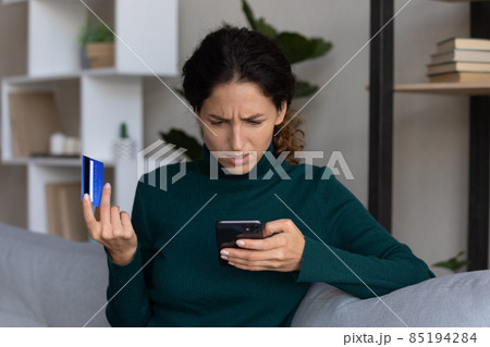 Concerned lady looking on smartphone having finance stolen from card Concerned lady looking on smartphone having finance stolen from card 85194284
