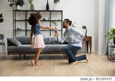 Happy African American father inviting for dance little kid daughter. 85194437