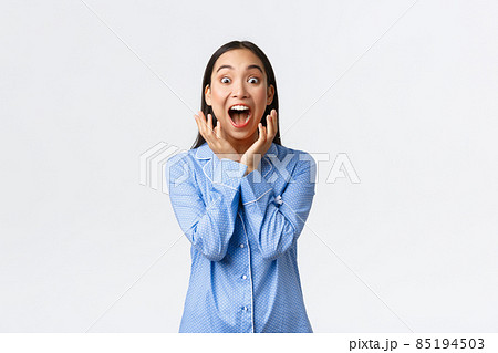 Excited super happy asian girl in blue pajamas waking up to awesome surprise, screaming from happiness looking at camera astounded, react to awesome gift, standing white background 85194503