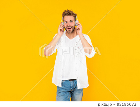 happy unshaven young man in headphones on yellow background, fashion 85195072