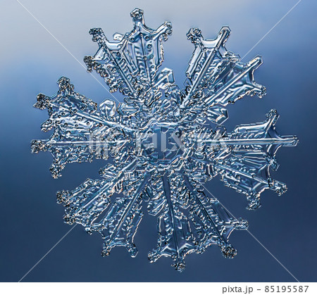 Snowflake on smooth gradient background. Macro photo of real snow crystal on glass surface. This is small snowflake with unusual pattern. 85195587