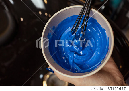 girl in white rubber protective gloves holding a brush in her hands and stirring hair dye close-up colorist. girl in white rubber protective gloves holding a brush in her hands and stirring hair dye close-up colorist. 85195637
