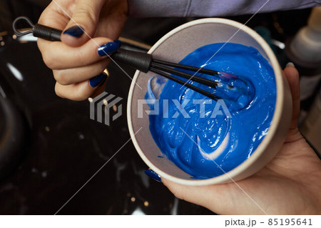 girl in white rubber protective gloves holding a brush in her hands and stirring hair dye close-up colorist. girl in white rubber protective gloves holding a brush in her hands and stirring hair dye close-up colorist. 85195641