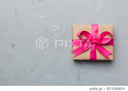 Holiday gift box wrapped in craft paper with colored bow on table background. Top view, flat lay, copy space Holiday gift box wrapped in craft paper with colored bow on table background. Top view, flat lay, copy space 85196604