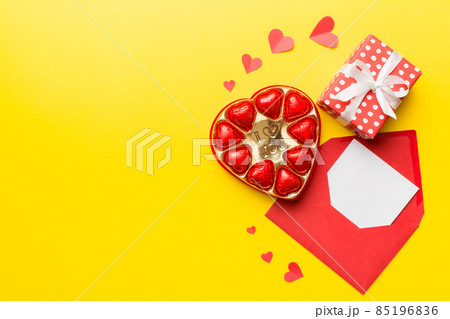 Envelope on colored background for Valentine Day with gift box and chocolate. Heart shaped with gift box of chocolates top view with copy space 85196836
