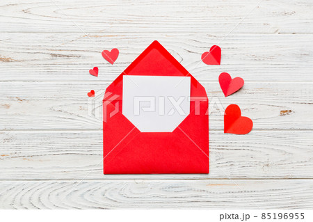 Red paper envelope with empty white card and heart on colored background. top view valentines day concept Red paper envelope with empty white card and heart on colored background. top view valentines day concept 85196955