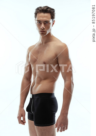 Half-length portrait of young handsome shirtless sportive man wearing black boxer-briefs standing isolated on white background. Half-length portrait of young handsome shirtless sportive man wearing black boxer-briefs standing isolated on white background. 85197081