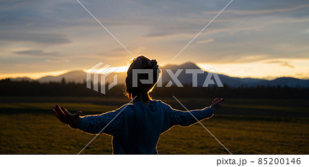 Young woman meditating in nature at sunset 85200146