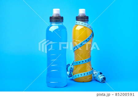 Isotonic energy orange yellow and blue sport drink in plastic bottles and measure tape 85200591