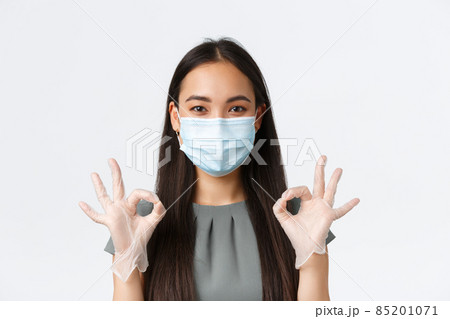 Small business owners, covid-19, preventing virus measures concept. Close-up of smiling pleasant asian female in medical mask and gloves, showing okay gesture as ensuring clients in safety Small business owners, covid-19, preventing virus measures concept. Close-up of smiling pleasant asian female in medical mask and gloves, showing okay gesture as ensuring clients in safety 85201071