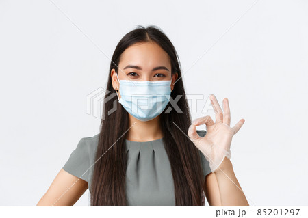 Small business owners, covid-19, preventing virus measures concept. Close-up of young asian businesswoman in medical mask and gloves guarantee safe delivery, no contact with packages, show ok gesture Small business owners, covid-19, preventing virus measures concept. Close-up of young asian businesswoman in medical mask and gloves guarantee safe delivery, no contact with packages, show ok gesture 85201297