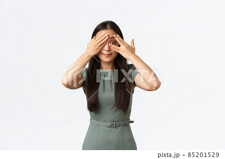 Small business owners, women entrepreneurs concept. Excited asian female in dress, smiling intrigued as shut eyes and peeking through fingers, anticipating surprise, standing white background Small business owners, women entrepreneurs concept. Excited asian female in dress, smiling intrigued as shut eyes and peeking through fingers, anticipating surprise, standing white background 85201529