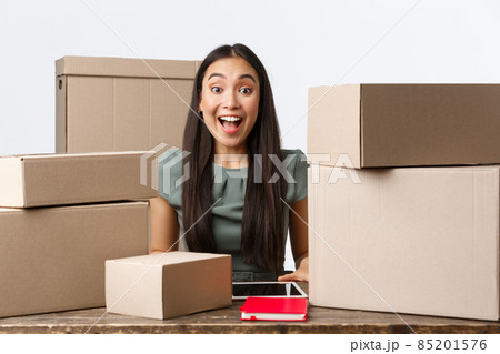 Small business owners, startup and e-commerce concept. Excited happy asian businesswoman receive big order, packing boxes for clients, shipping parcels, working from home in online store 85201576