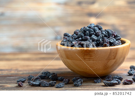 Dark raisins in a wooden bowl. 85201742